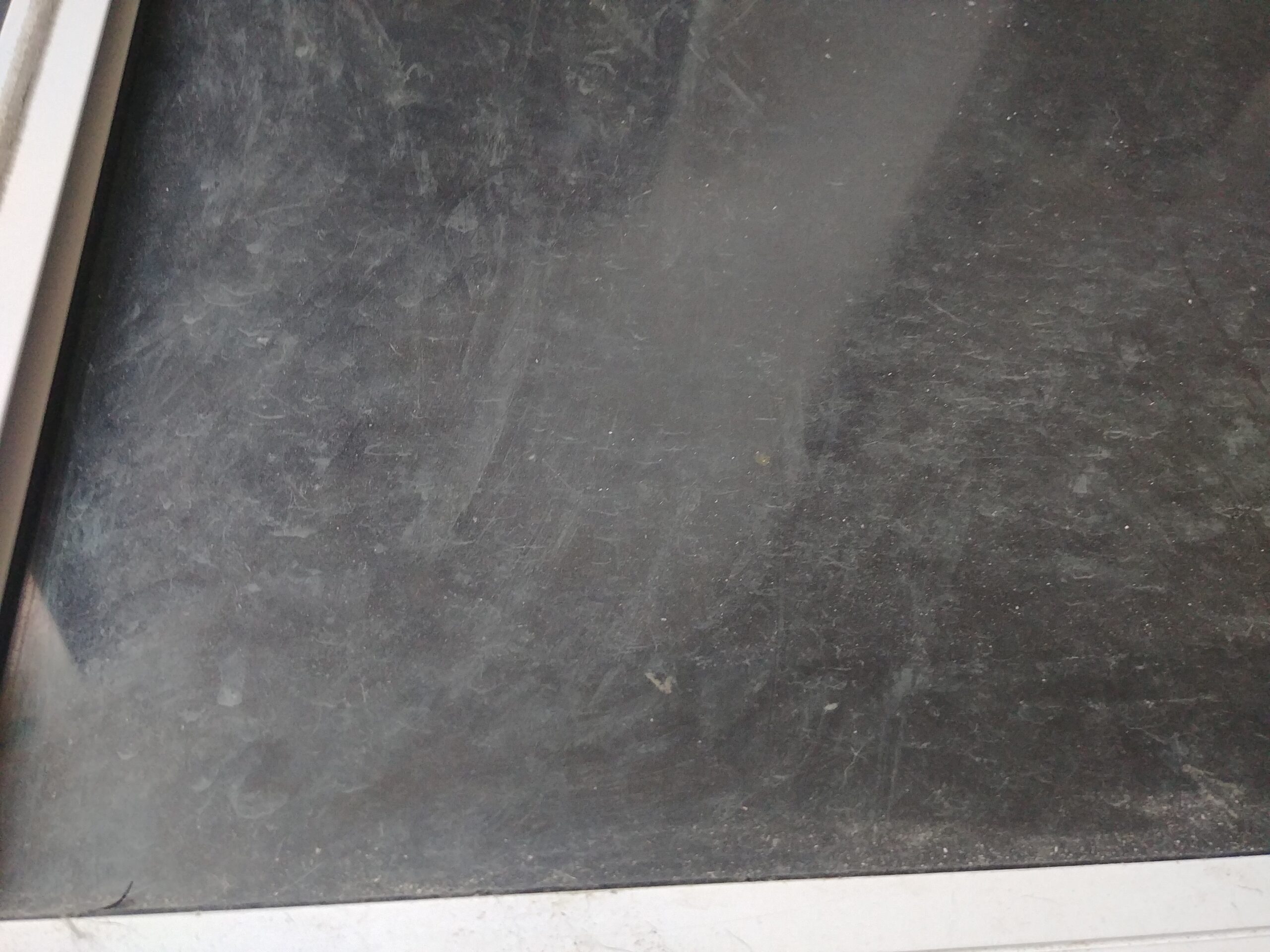 Dirty glass window pane with cloudy smudges, dust, and fingerprints before cleaning with homemade window cleaner.