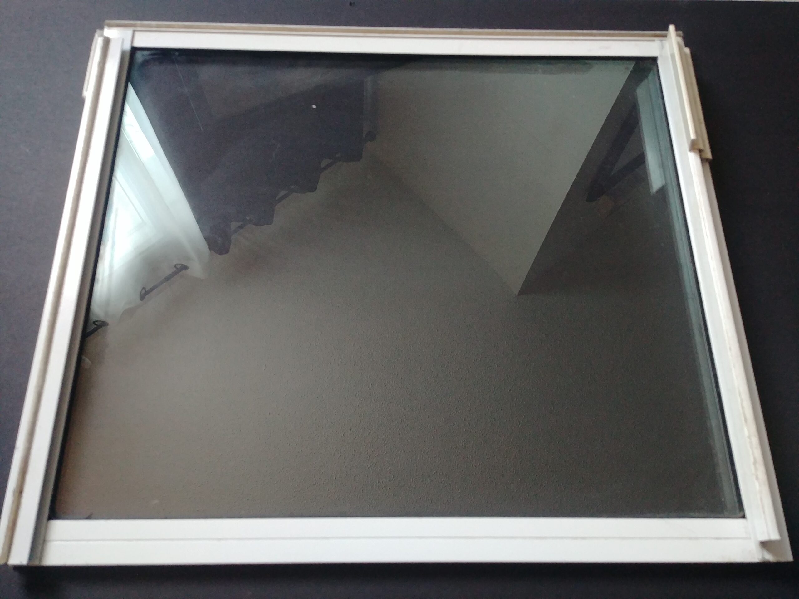 Close-up of a white-framed glass window pane with reflections, ready for cleaning with homemade eco-friendly window cleaner.