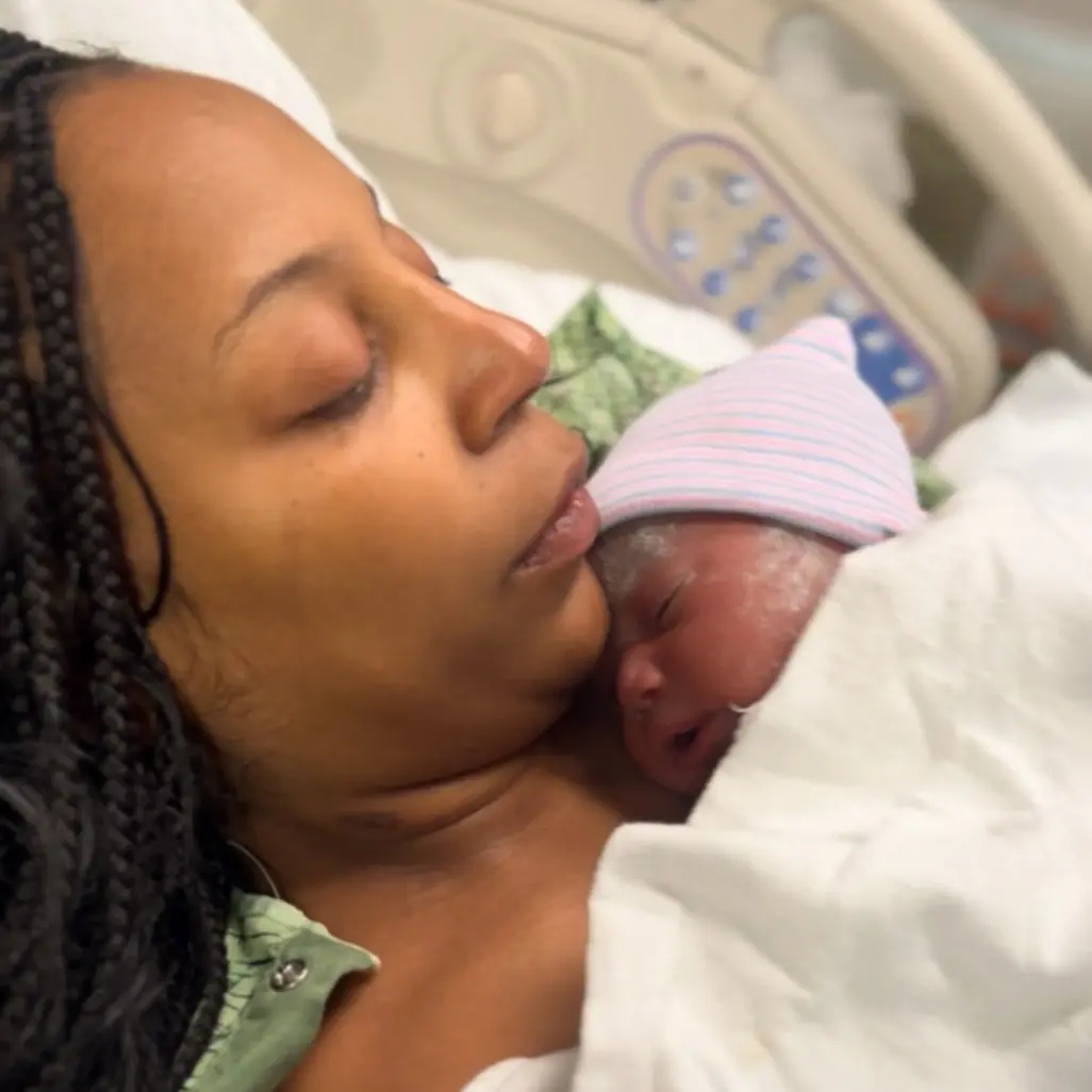 Mother cuddling her newborn baby in a hospital bed shortly after birth, a tender skin-to-skin moment in maternity care.