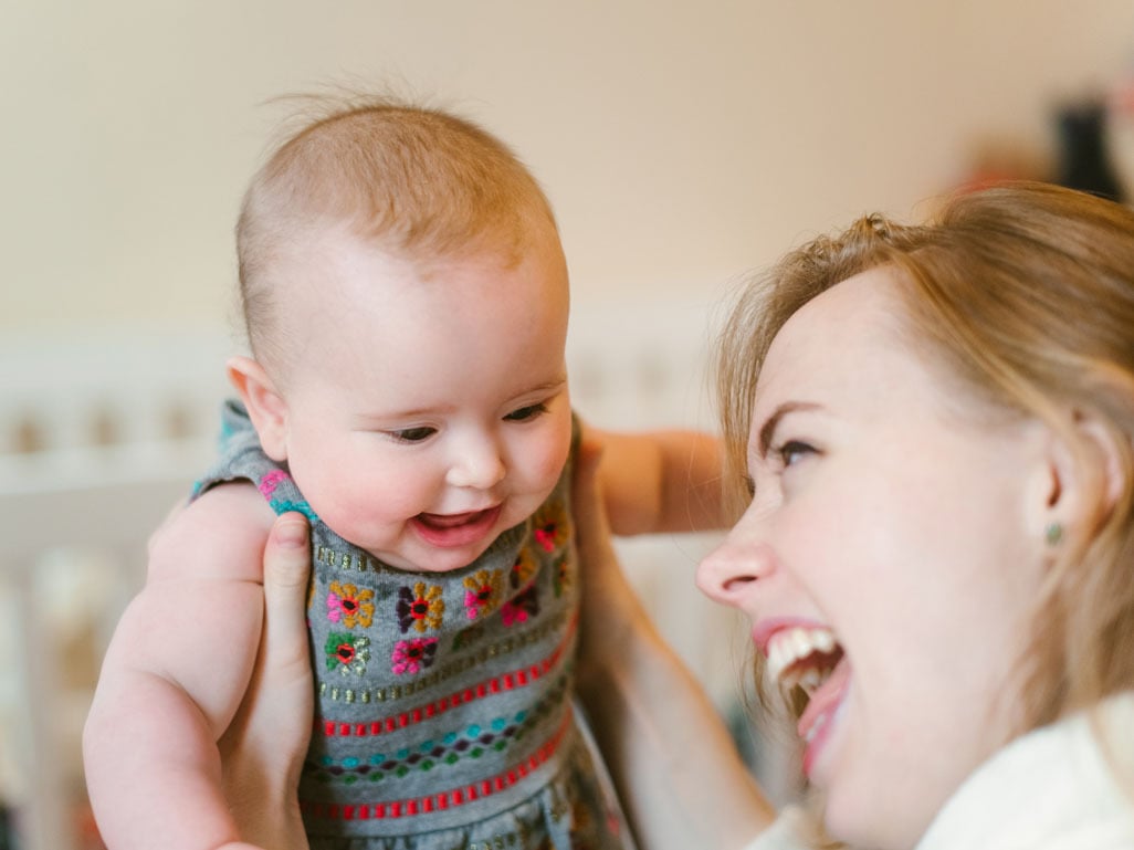 Smiling mother interacting with her baby at home, highlighting early bonding, communication, and infant hearing and language development.