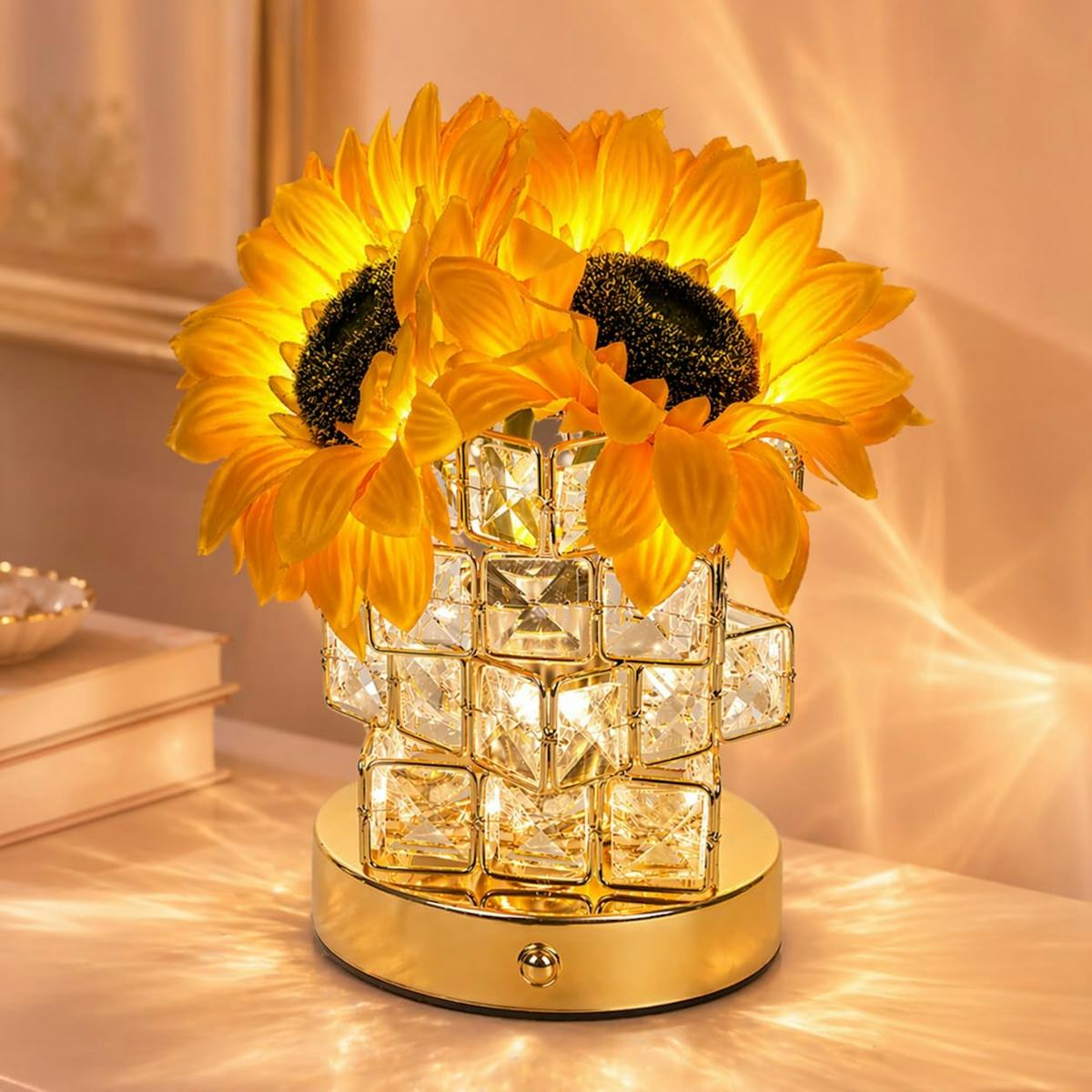 Glowing sunflower table lamp with faux yellow flowers, crystal-style vase, and gold base casting warm light patterns on a tabletop.