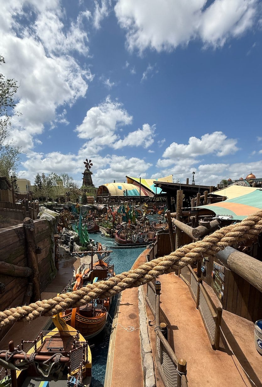 Viking-themed Isle of Berk water ride area at Universal Epic Universe with wooden boats, rope railings, colorful canopies, and blue sky.