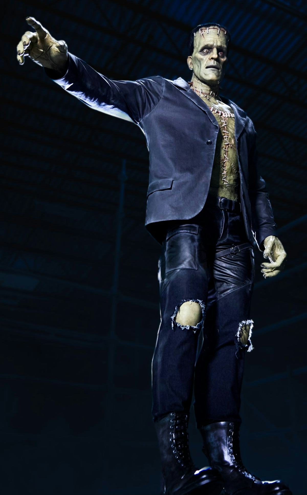 Frankenstein's monster figure in a dark suit reaches forward inside Universal Epic Universe's Dark Universe attraction.
