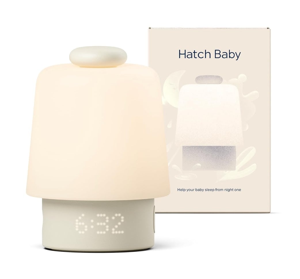 Glowing Hatch Baby sound machine with digital clock beside its product box, a minimalist nursery sleep aid for baby registry essentials.
