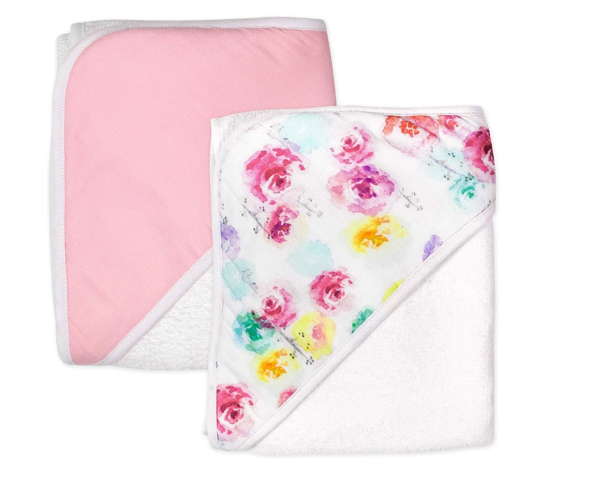 Two folded baby hooded towels, one soft pink and one white with a colorful floral print, displayed on a clean white background.