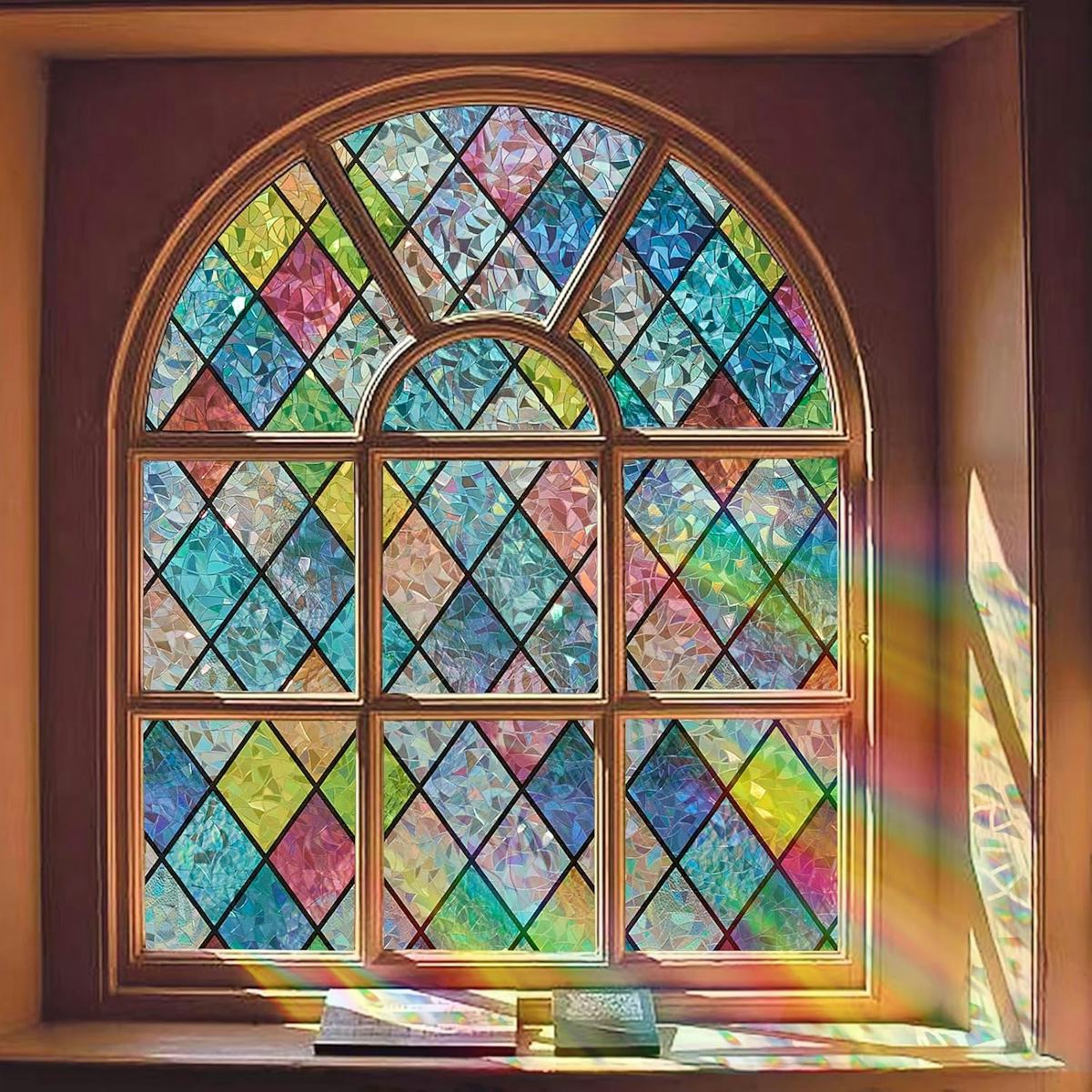 Decorative stained glass window film with colorful diamond panes on an arched wooden window, casting rainbow light indoors.