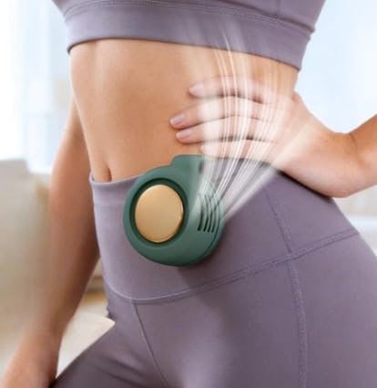Woman in gray activewear wearing a compact green clip-on personal fan on her waistband, with airflow lines showing cooling breeze.