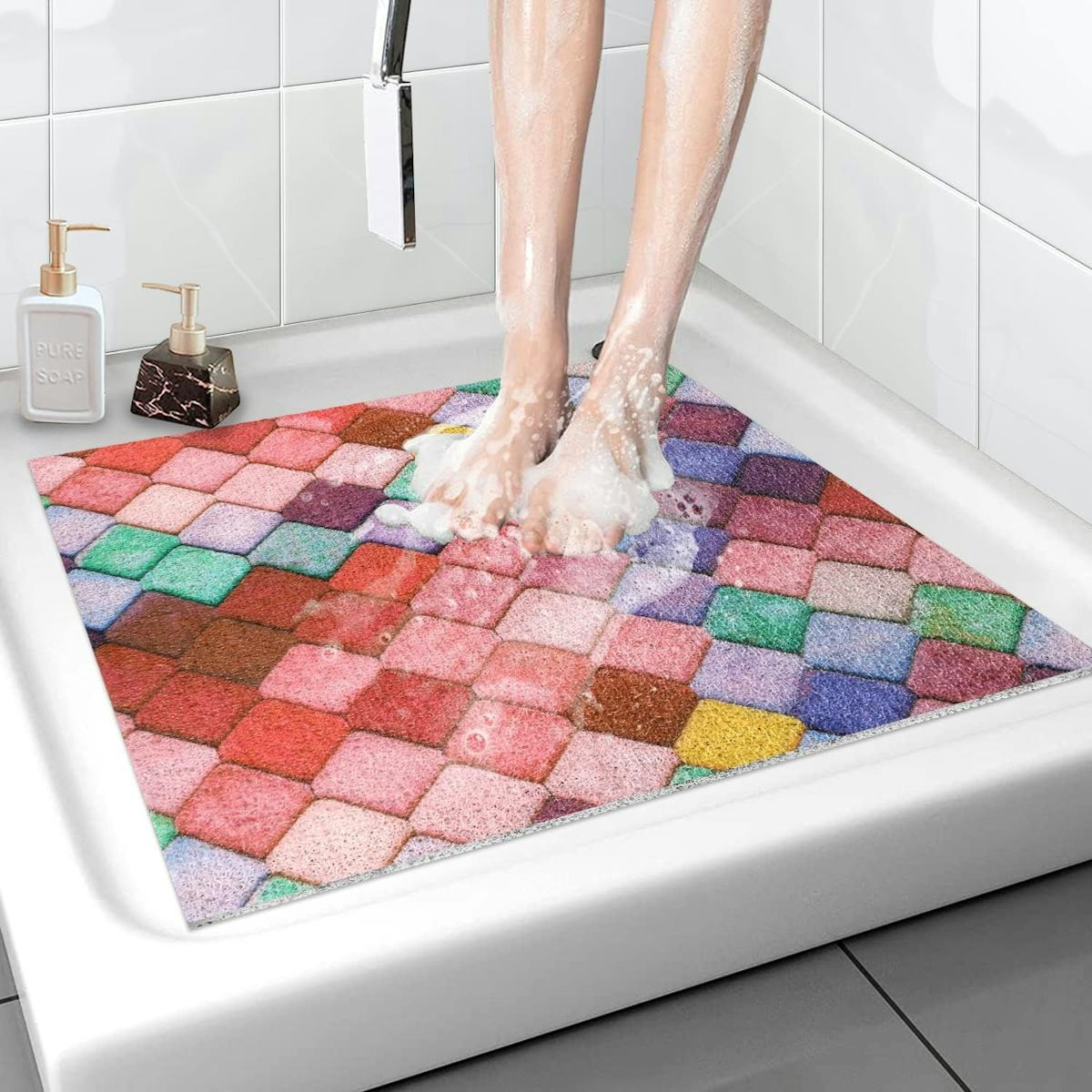 Colorful nonslip shower mat with a rainbow tile pattern under soapy feet in a white tiled shower, adding comfort and bathroom safety.