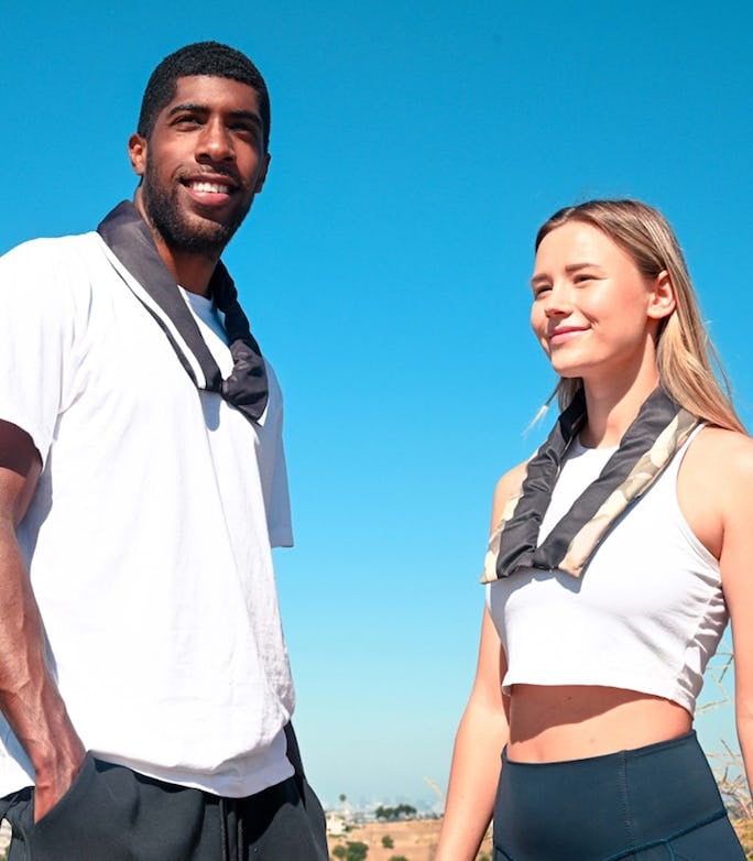 Two people outdoors in activewear wearing neck cooling wraps under a bright blue summer sky.