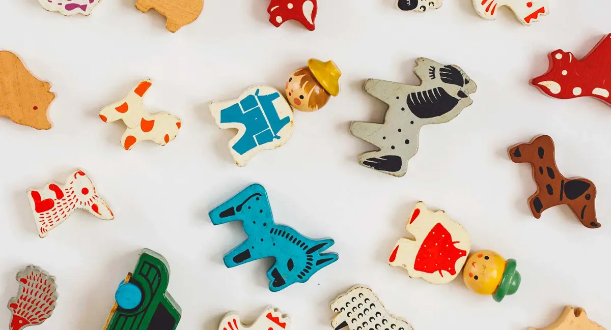 Assorted colorful vintage wooden animal toys scattered on a white background, evoking classic nursery playthings and baby name nostalgia.