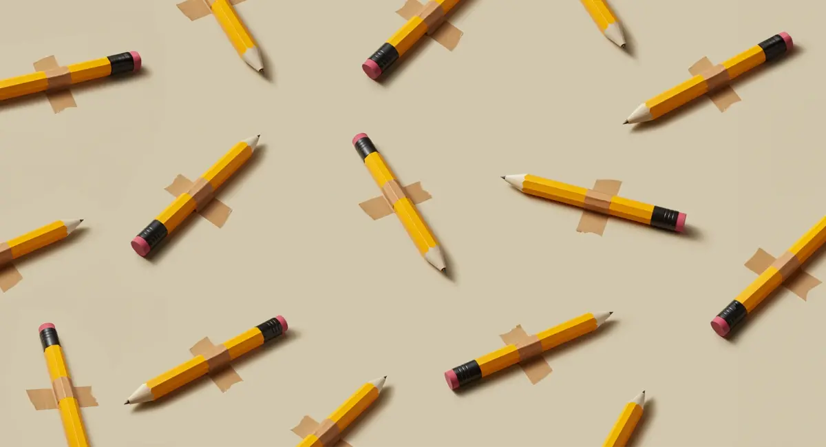 Yellow pencils taped to a beige background, arranged in a playful scattered pattern for baby name inspiration or school-themed content.