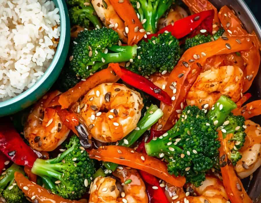 Shrimp and vegetable stir-fry with broccoli, peppers, carrots, sesame seeds, and rice