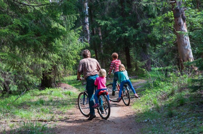 Adult and three children with bicycles on a wooded dirt trail