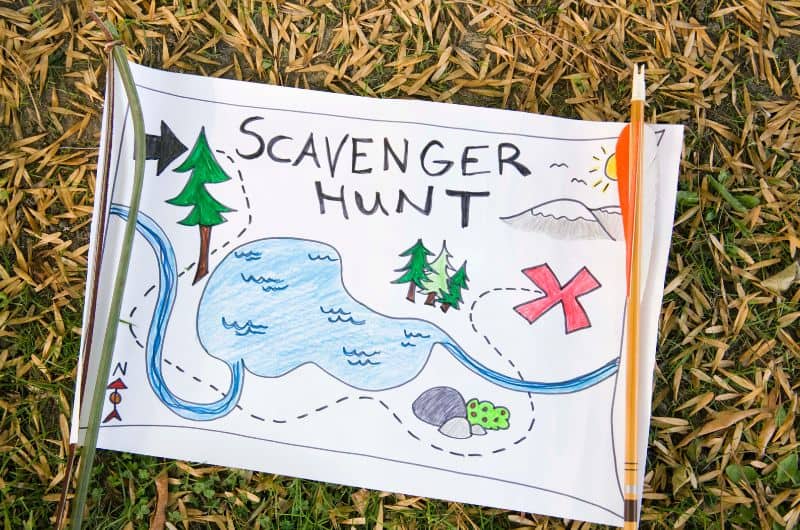 Hand-drawn scavenger hunt map on paper with a pencil, lying on grass and straw