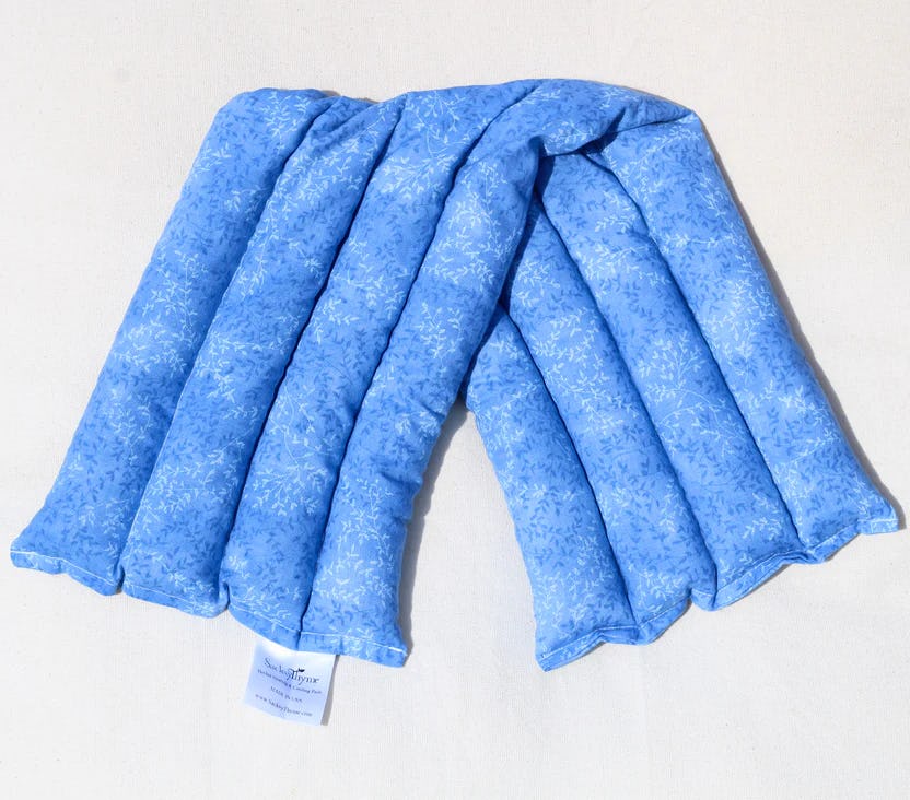 Blue floral quilted pad laid in a loose U shape on a light fabric surface with a small tag.