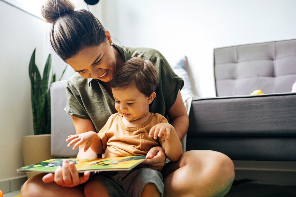 Woman sitting with a young child and looking at an open picture book together