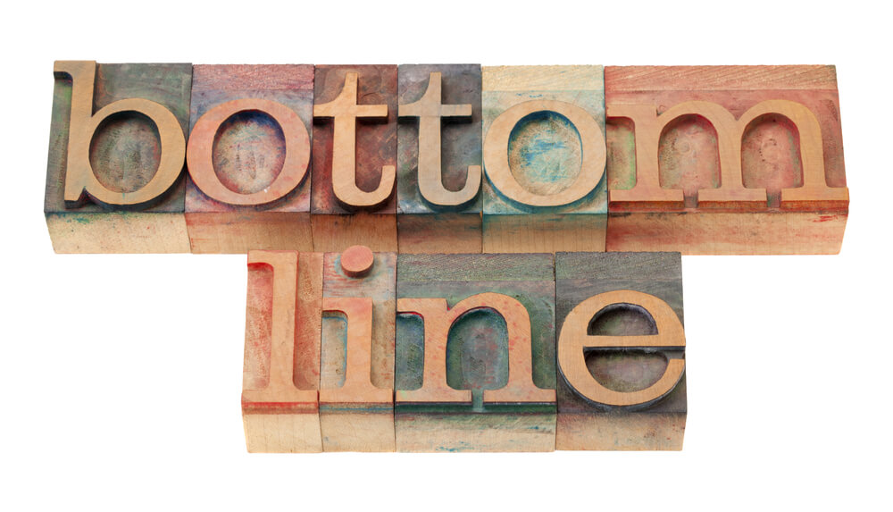 Wooden letterpress blocks spelling "bottom line" on a white background.