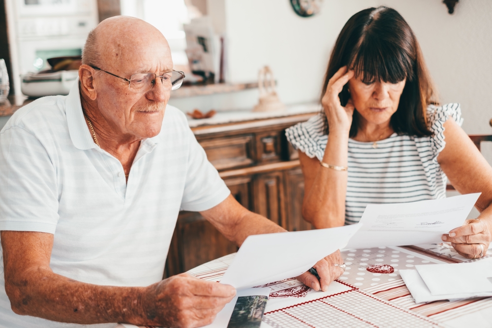 Older man and woman sitting at a table reviewing papers together