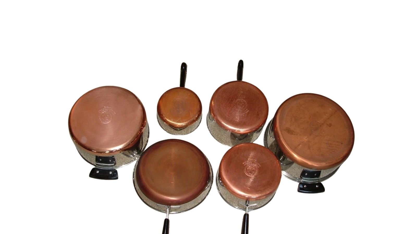Copper-bottom cookware set arranged on a white background