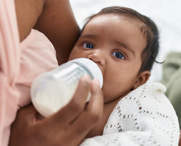 Baby being bottle-fed while held close in an adult's arms