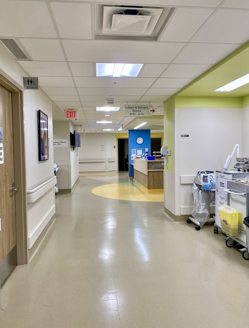 Hospital hallway with signs for Labour & Delivery Rooms and staff washroom near a nurses station