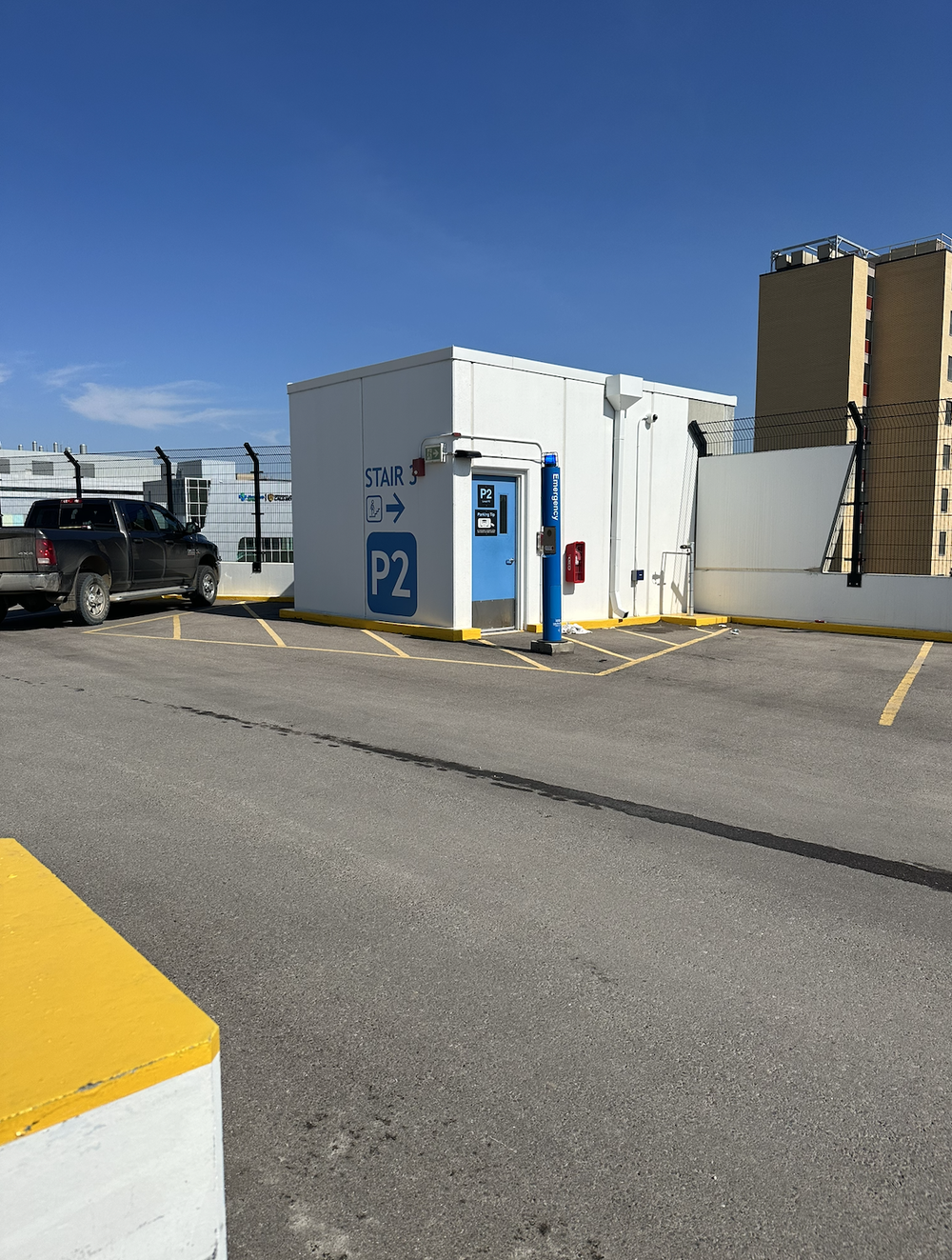 Rooftop parking area with a white stairwell structure marked STAIR and P2 beside a blue door.