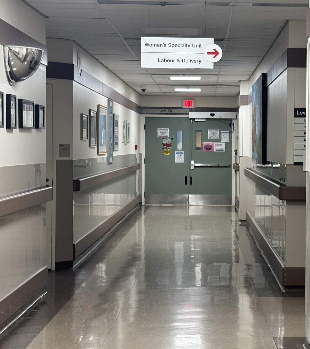 Hospital hallway with signs for Women's Specialty Unit and Labour & Delivery pointing right
