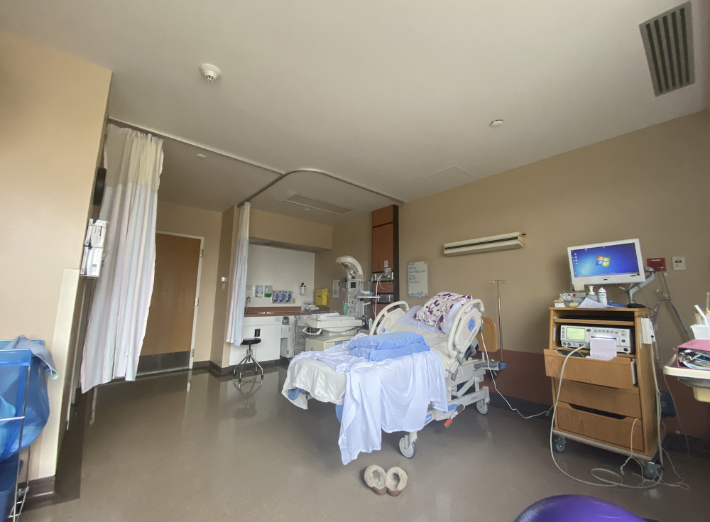 Hospital room with an adjustable bed, privacy curtains, medical equipment, and a computer monitor