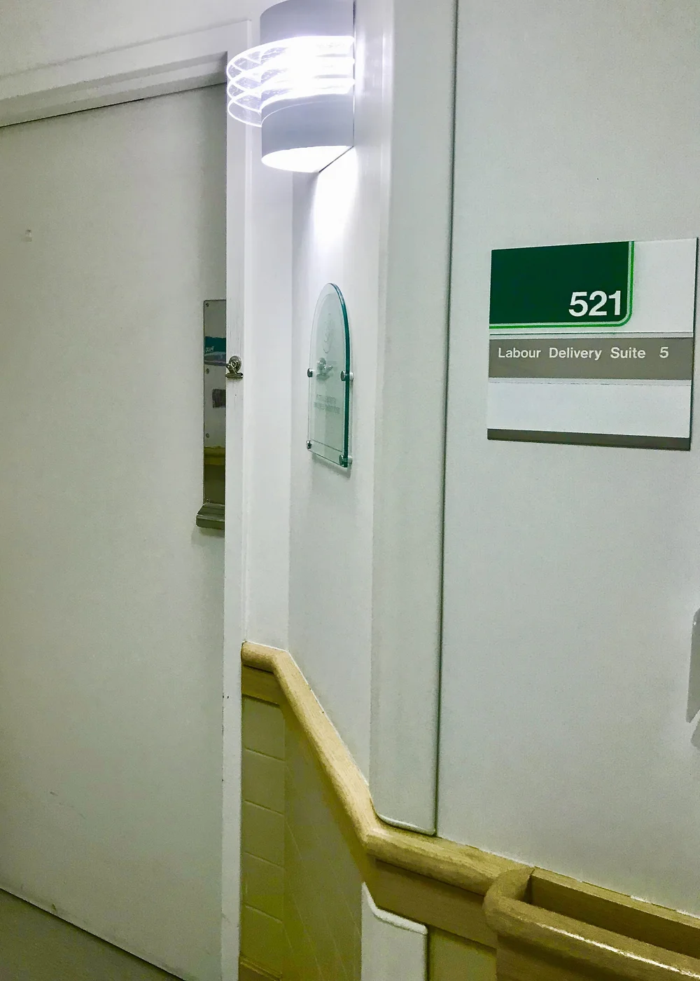 Hospital corridor sign reading 521 Labour Delivery Suite 5 beside a doorway and wall light.