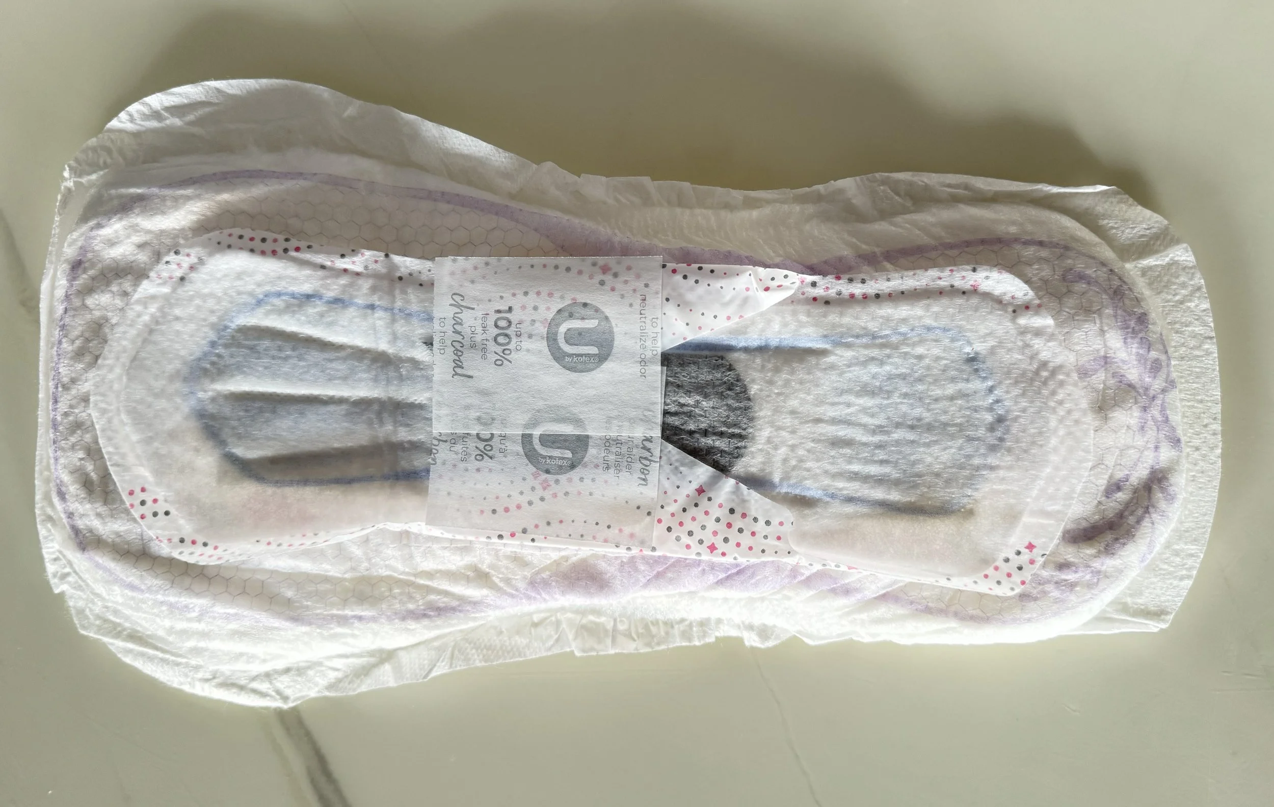 Opened absorbent pad laid inside white disposable underwear on a pale surface.