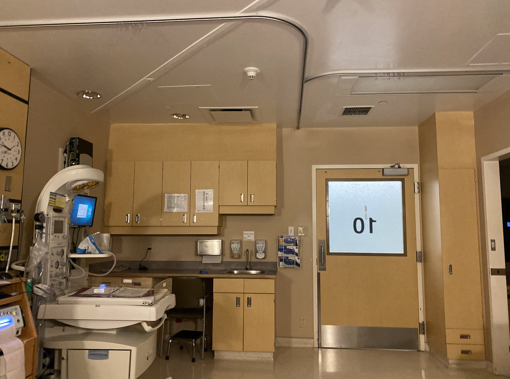 Hospital room with infant warmer, cabinets, sink, and door marked 10