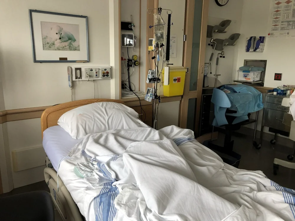 Hospital room with an empty bed, medical equipment, and a prepared exam table