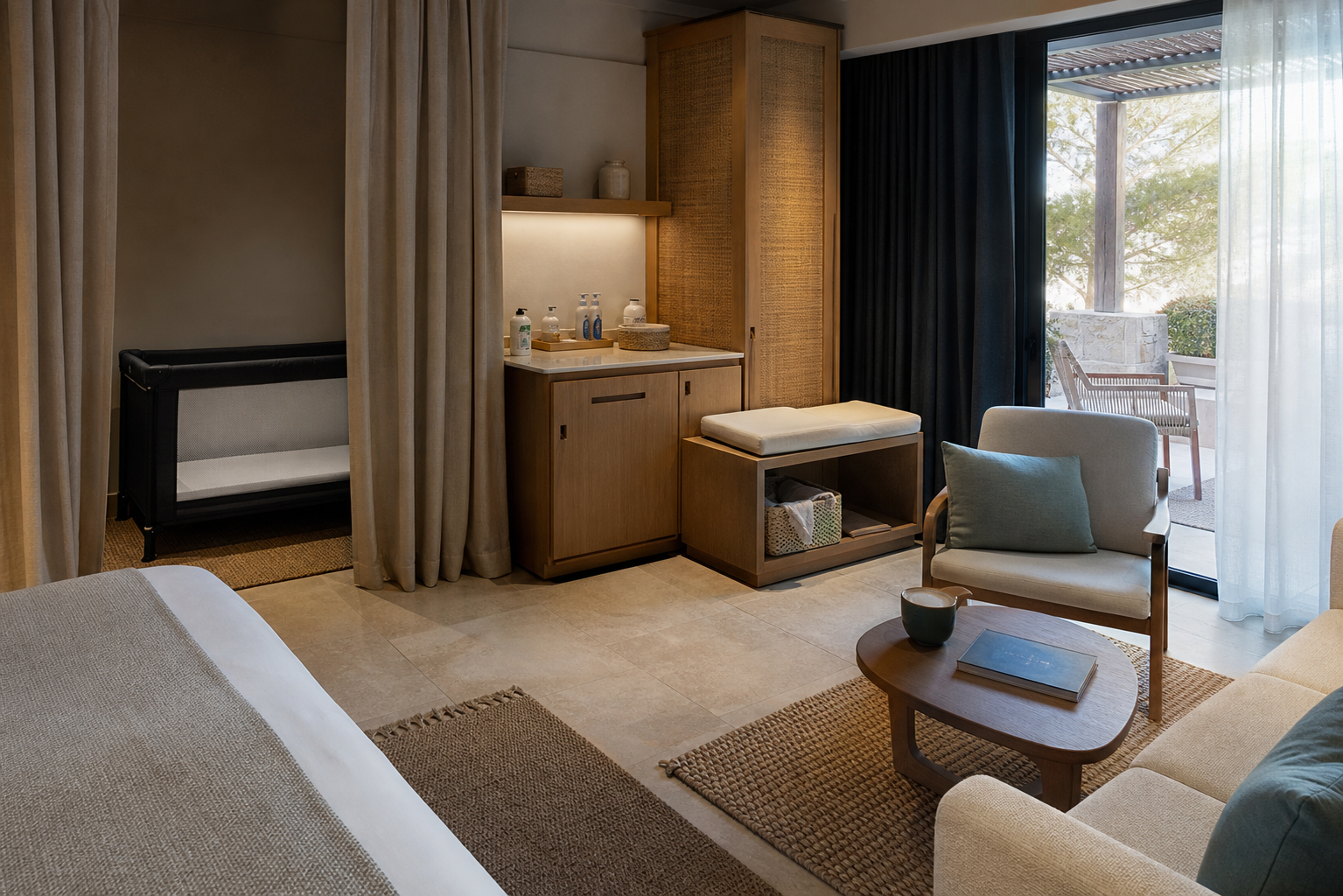 A Mediterranean-style family room has a travel cot in a curtained sleeping alcove, a separate sitting area, blackout drapes, and a shaded terrace.